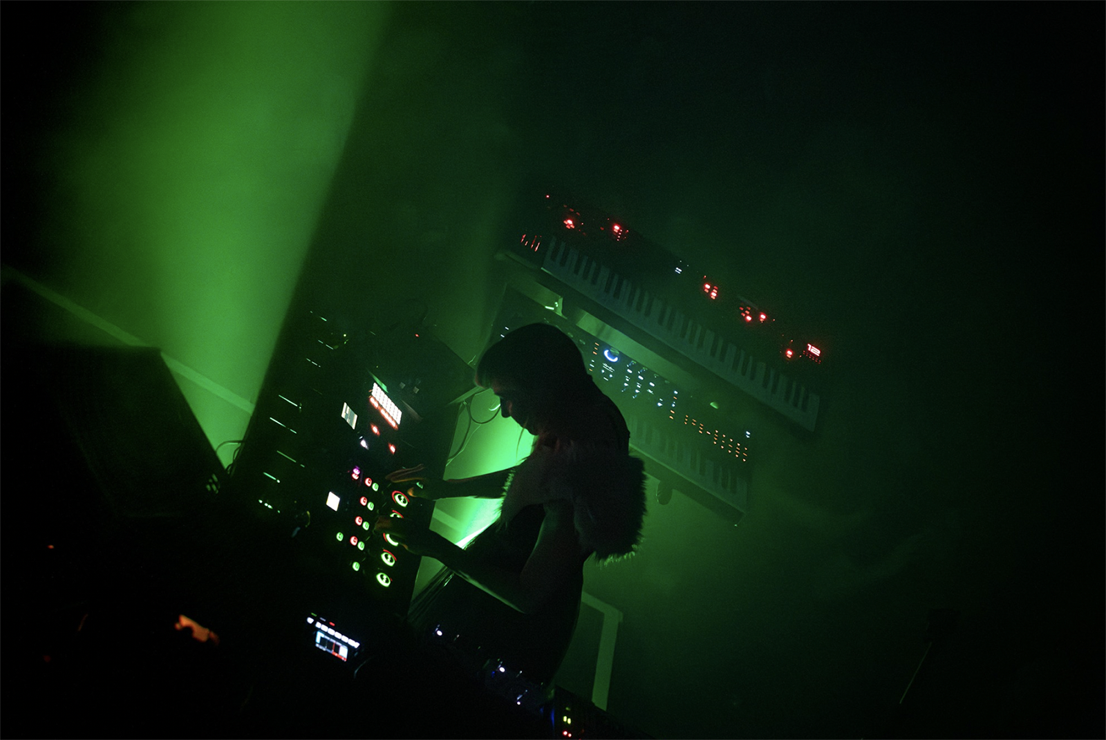 A photo from Modulation that captures a DJ is performing with green lights around